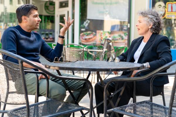 Two people sitting outdoors engaged in conversation.